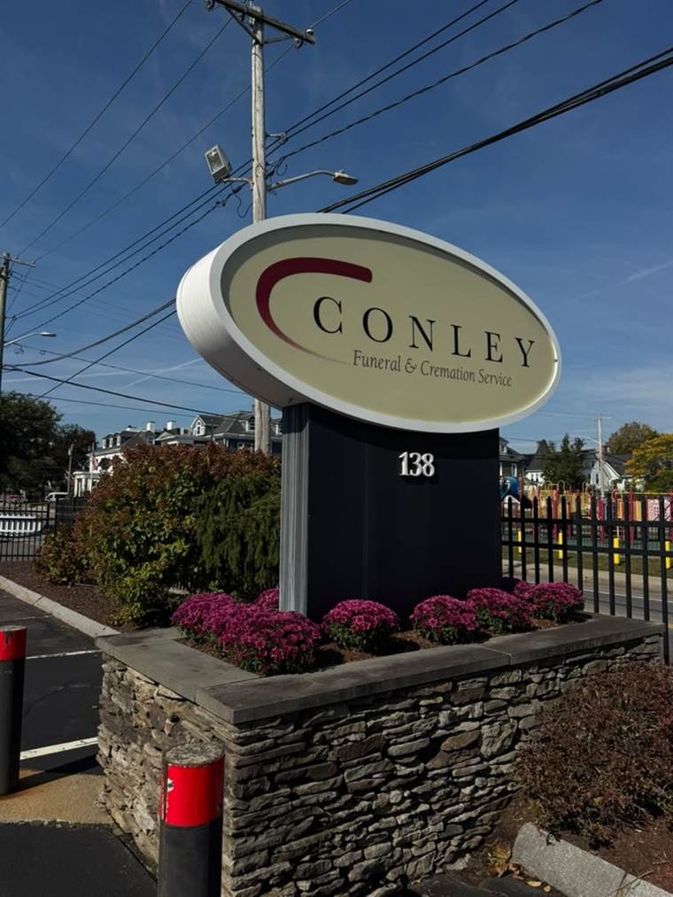 Stone planter wall and seasonal mums at Conley Funeral & Cremation Service maintained by Vcoelho General Services